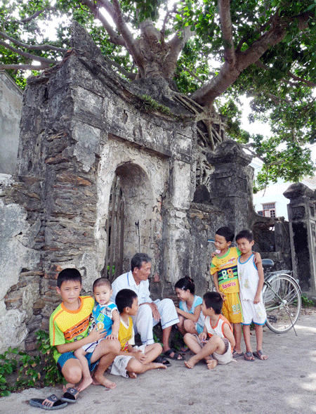 Cụ ông Ngô Xuân Lương kể chuyện xưa cho thế hệ các cháu bên miếu cổ Thành Hoàng làng.
