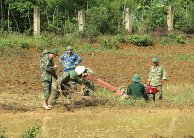 Đồng dưới các chiến sĩ Đồn Biên phòng Cà Xèng tập trung lực lượng giúp dân làm đất.