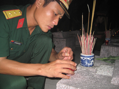 Một sỹ quan quân đội nhân dân trẻ bên phần mộ đồng đội mình