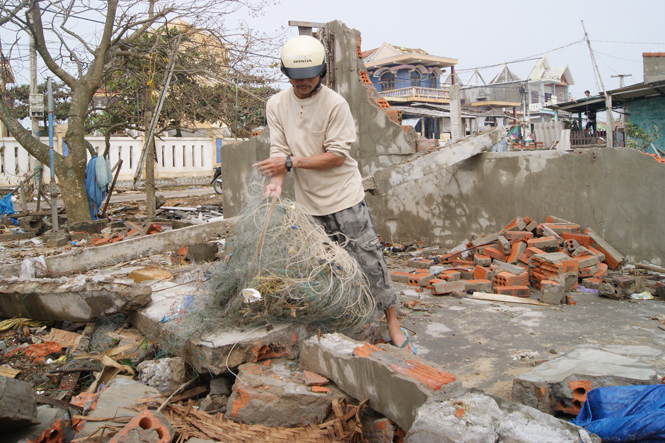 Anh Nguyễn Văn Ninh nhặt nhạnh những mảnh lưới còn sót lại trên nền ngôi nhà đổ nát