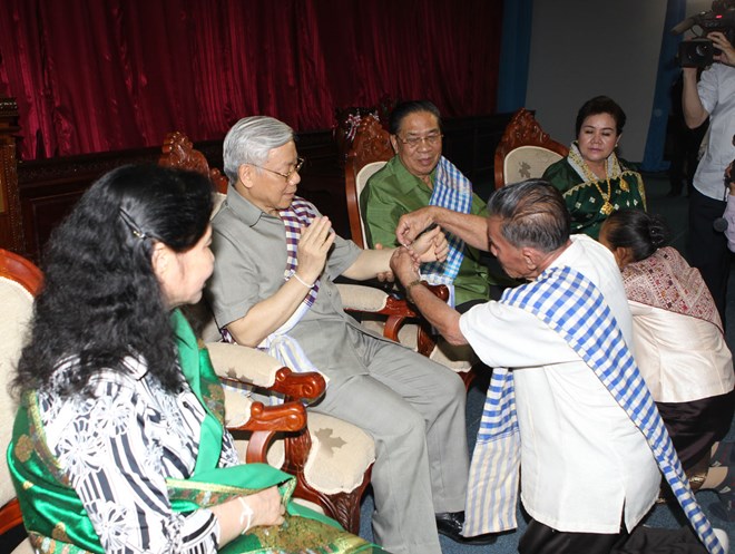 Tổng Bí thư Nguyễn Phú Trọng và Phu nhân cùng Tổng Bí thư, Chủ tịch nước Lào Chummaly Sayasone và Phu nhân dự Lễ buộc chỉ cổ tay chúc phúc. (Ảnh : Trí Dũng/TTXVN)