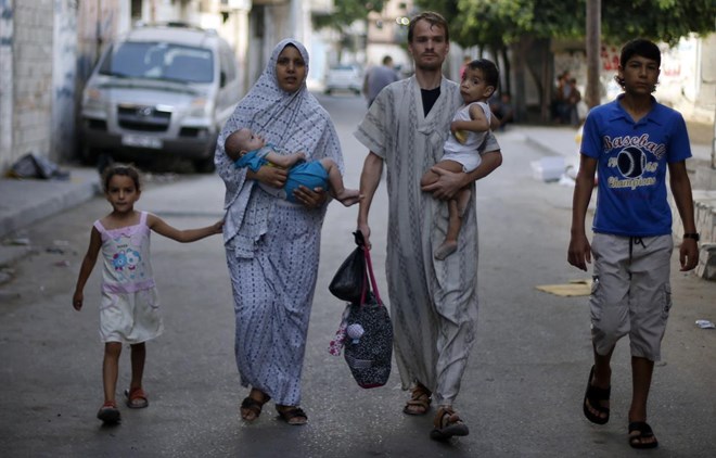 Người dân ở dải Gaza đưa con đi sơ tán sau những đợt tấn công của Israel (Nguồn: AFP)
