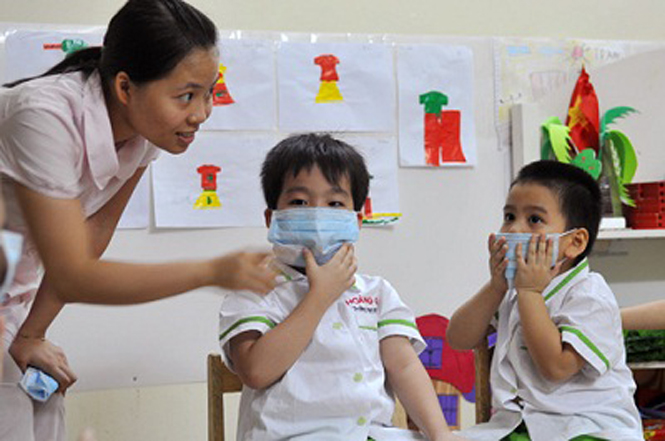 Hướng dẫn trẻ đeo khẩu trang để phòng bệnh cúm.