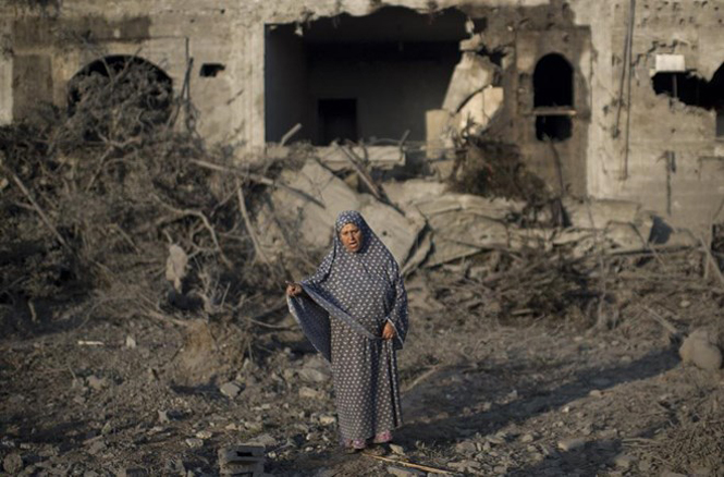 Một phụ nữ Palestine đứng trước ngôi nhà bị đạn pháo Israel phá sập (Nguồn: AFP)