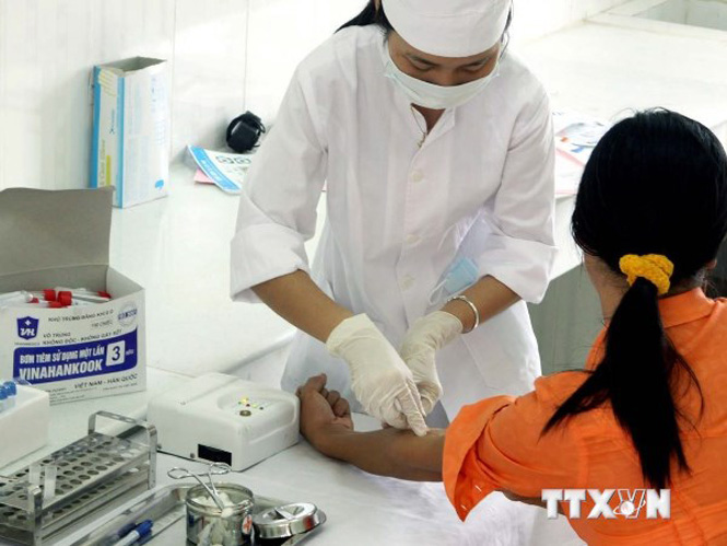 Cán bộ y tế của Trung tâm phòng chống HIV/AIDS lấy mẫu máu xét nghiệm HIV/AIDS cho người dân. (Ảnh: TTXVN)