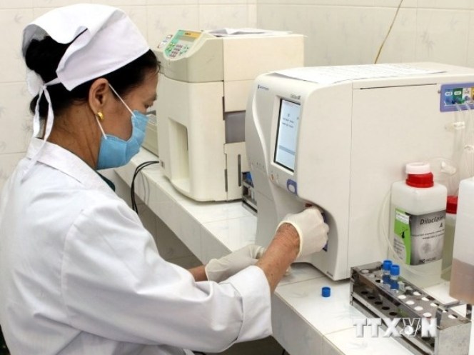  Nhân viên y tế sử dụng hệ máy xét nghiệm sinh hóa tự động trong công tác chẩn đoán bệnh. (Ảnh: TTXVN)