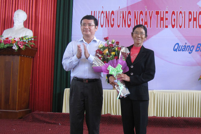 Đồng chí Trần Tiến Dũng, TUV, Phó Chủ tịch UBND tỉnh, tặng hoa chúc mừng chị Nguyễn Thị Toan, cộng tác viên phòng chống HIV/AIDS tích cực.