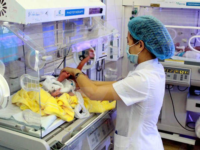 Nhân viên y tế chăm sóc cho trẻ mới sinh. (Ảnh: TTXVN)