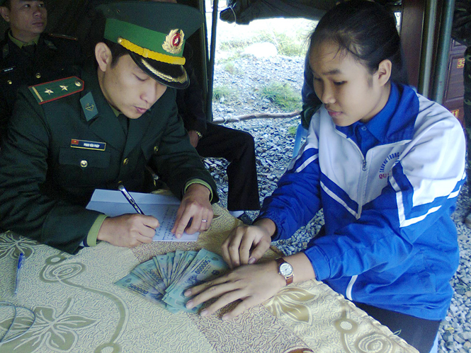 Học sinh Lê Thị Phương Ly bàn giao số tiền 18 triệu đồng cho cán bộ Đồn Biên phòng Roòn để trả lại người bị mất.
