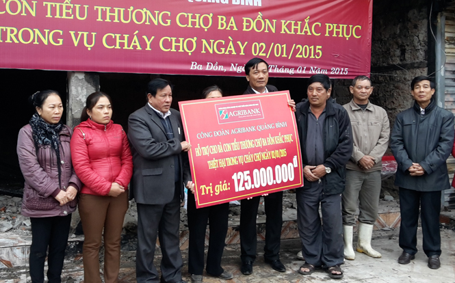 Ông Nguyễn Duy Phú, Giám đốc Chi nhánh Agribank huyện Quảng Trạch trao tiền hỗ trợ cho các hộ tiểu thương bị thiệt hại