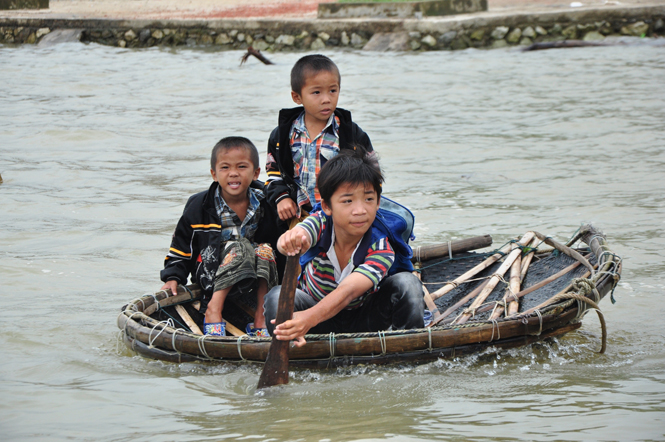 Ba đứa trẻ tự chèo thuyền thúng trên sông.
