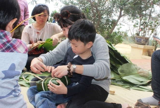 Chắt ngoại Bùi Việt Thiện Quang (5 tuổi) được mẹ dạy cho cách gói bánh chưng