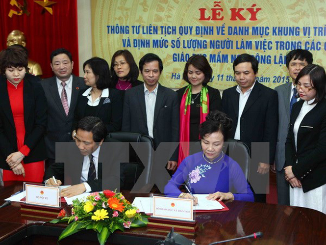 Thứ trưởng Bộ Giáo dục và Đào tạo Nguyễn Thị Nghĩa (phải) ký Thông tư liên tịch với Thứ trưởng Bộ Nội vụ Trần Anh Tuấn tại buổi lễ. (Ảnh: Quý Trung/TTXVN)