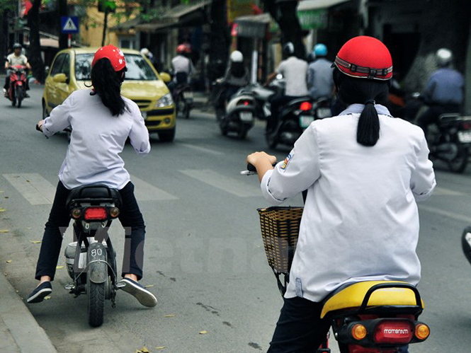 Từ ngày hôm nay, toàn quốc bắt đầu xử phạt hành vi không đội mũ bảo hiểm cho trẻ em khi đi xe gắn máy, xe đạp điện (Ảnh: Võ Phương/Vietnam+)