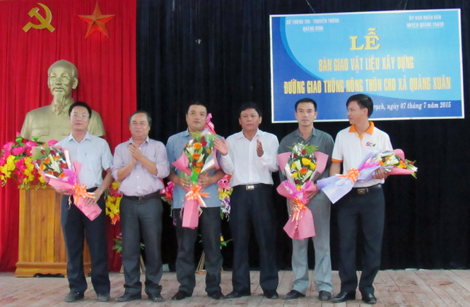 Lãnh đạo Sở Thông tin-Truyền thông và huyện Quảng Trạch tặng hoa cho các doanh nghiệp tài trợ xi măng.