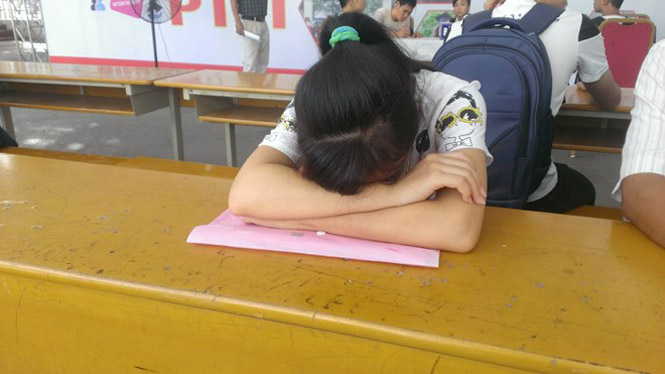 Thí sinh mệt mỏi gục xuống bàn tại Học viện Công nghệ Bưu chính viễn thông sáng 17-8. (Ảnh: Phạm Mai/Vietnam+)