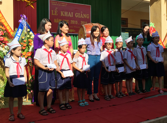 Chị Cao Thị Hồng Vân (người đứng giữa hàng) trao các suất quà cho các em học sinh nghèo học giỏi tại Trường tiểu học số 3 Nam Lý.