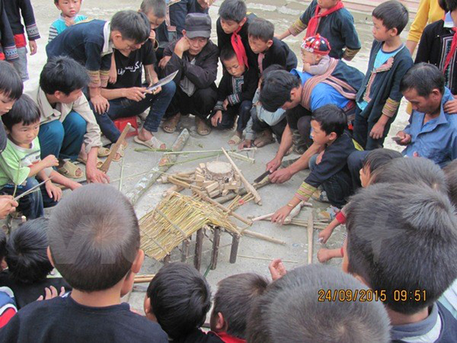 Các học sinh nam vây quanh các phụ huynh để học cách làm nhạc cụ, vật dụng truyền thống. (Ảnh: PM/Vietnam+)
