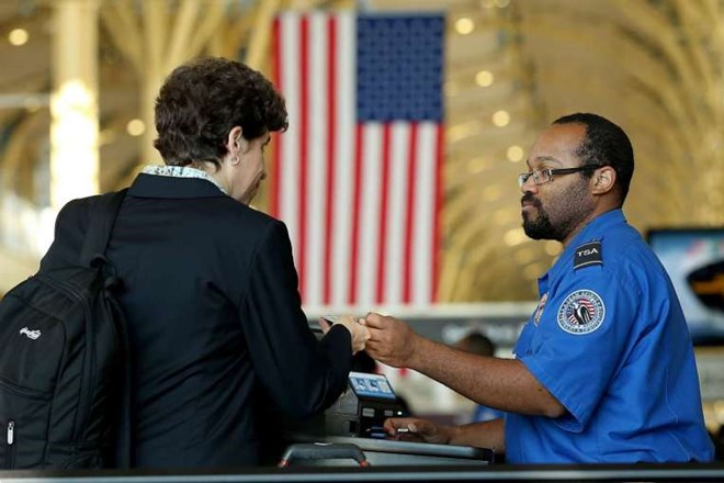 Một nhân viên an ninh kiểm tra giấy tờ của hành khách tại sân bay quốc gia Reagan, Mỹ. (Nguồn: AFP)