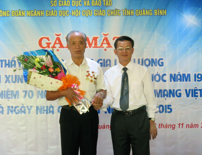 Đồng chí Đoàn Đức Liêm, Giám đốc Sở GD-ĐT tặng hoa chúc mừng thầy giáo Dương Văn Thiện, đại diện thế hệ nhà giáo-TNXP những năm đánh Mỹ tại buổi gặp mặt sau nửa thế kỷ.