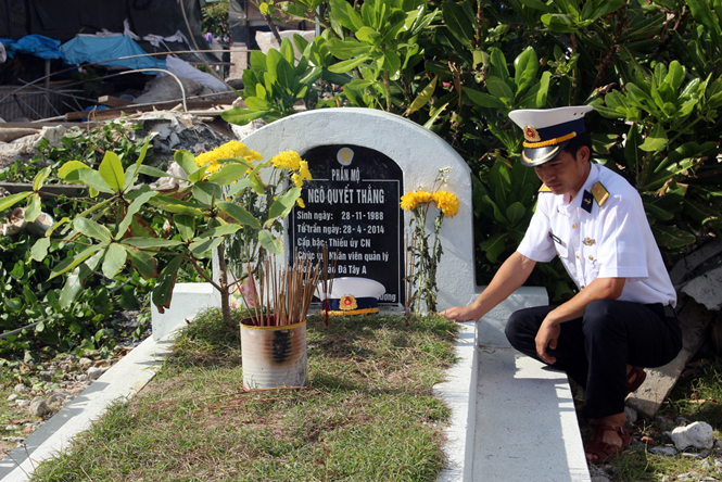 Thiếu úy Lê Nghiêm Nam bên mộ bạn thân Ngô Quyết Thắng trên đảo Trường Sa Đông.