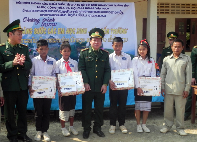 Đại diện Đồn Biên phòng CKQT Cha Lo trao quà cho các học sinh Lào.  