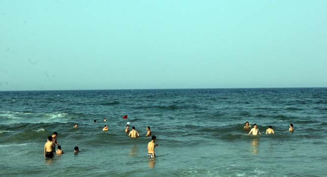 Rất đông du khách và người dân địa phương, trong đó có nhiều phụ nữ và trẻ em tắm biển.