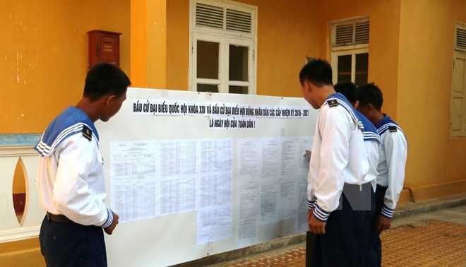 Các chiến sỹ trẻ, những người lần đầu tiên được tham gia bầu cử, xem bảng niêm yết danh sách cử tri. (Ảnh: Hứa Chung/TTXVN)