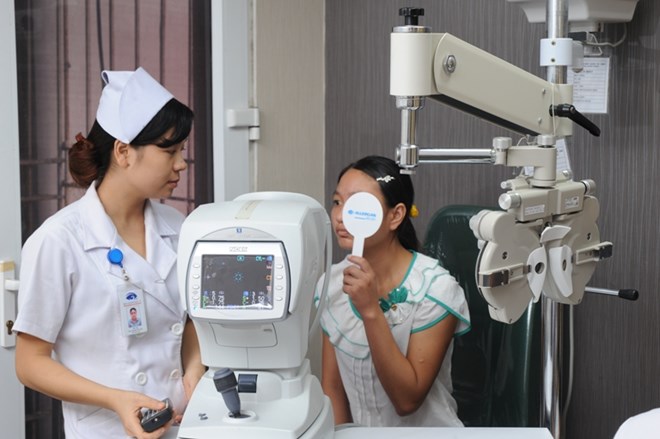 Nhân viên y tế kiểm tra mắt cho trẻ em. (Ảnh: PV/Vietnam+)