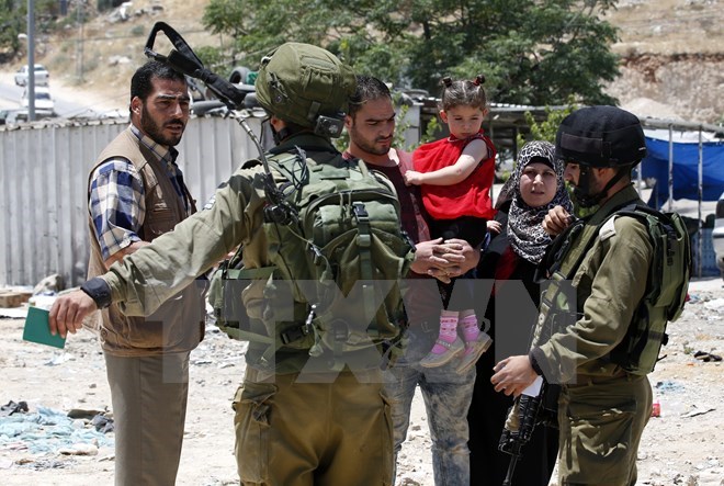 Binh sỹ Israel kiểm tra một gia đình Palestine tại một trạm kiểm soát ở Yatta, phía Nam Hebron. (Nguồn: EPA/TTXVN)