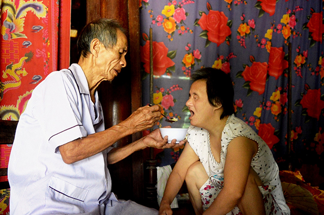 Ông Trương Đình Thắt đang cho cô con gái bị mù ăn cơm.