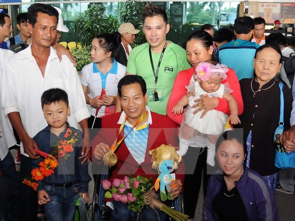 Vận động viên Lê Văn Công - HCV Paralympic Rio 2016 và phá kỷ lục thế giới môn cử tạ bên cạnh gia đình và người hâm mộ. (Ảnh: An Hiếu/TTXVN)
