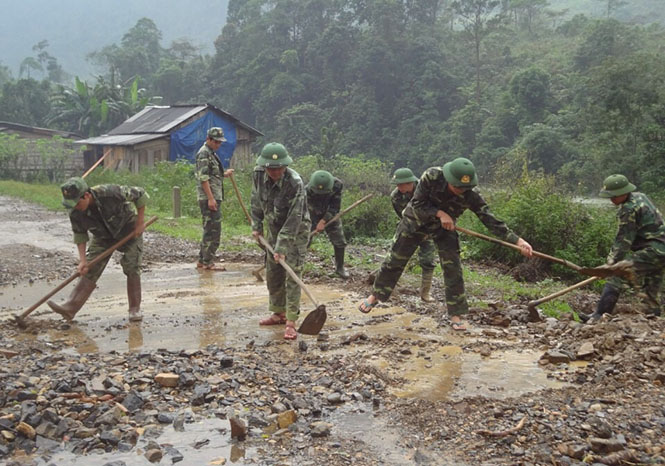 Cán bộ chiến sĩ Đồn Biên phòng Cà Xèng giúp dân nạo vét bùn ở những con đường trong thôn bản.