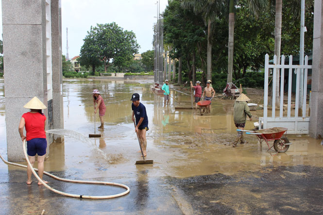 Mặc dù nước vẫn chưa rút hẳn nhưng người dân vẫn tranh thủ làm vệ sinh trước cổng Trung tâm văn hóa huyện Lệ Thủy.
