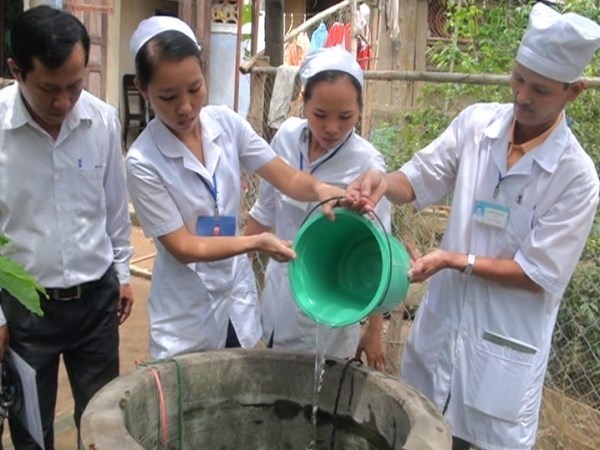 Nhân viên y tế xử lý giếng nước bằng hóa chất khử khuẩn tại vùng lũ của tỉnh Quảng Nam. (Ảnh: Hữu Trung/TTXVN)