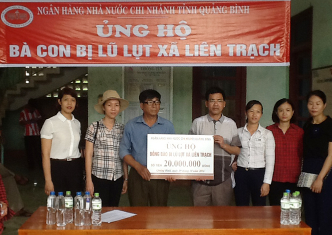 Ông Đinh Quang Hiếu- Giám đốc NHNN Chi nhánh Quảng Bình trao tiền ủng hộ cho UBND xã Liên Trạch, huyện Bố Trạch.
