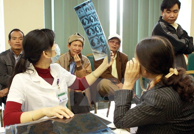 Nhân viên y tế khám, tư vấn bệnh về phổi, hô hấp cho một bệnh nhân nữ. (Ảnh: TTXVN/Vietnam+)