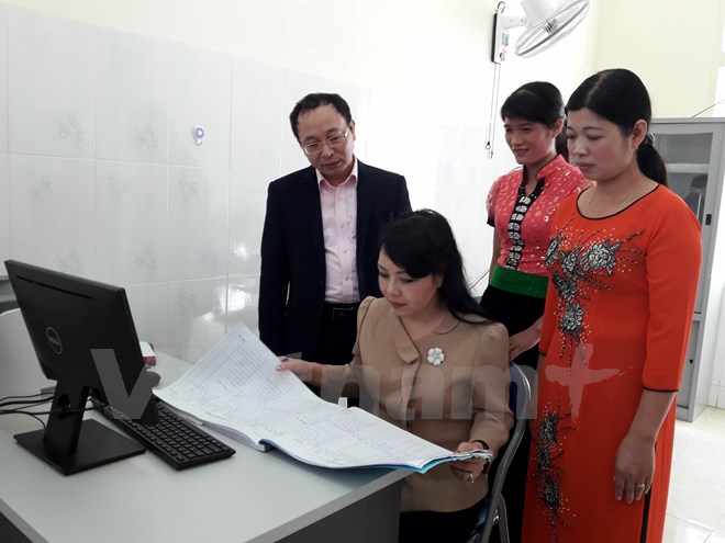 Bộ trưởng Bộ Y tế kiểm tra sổ khám bệnh tại Trạm Y tế Xã Chiềng Yên. (Ảnh: PV/vietnam+)
