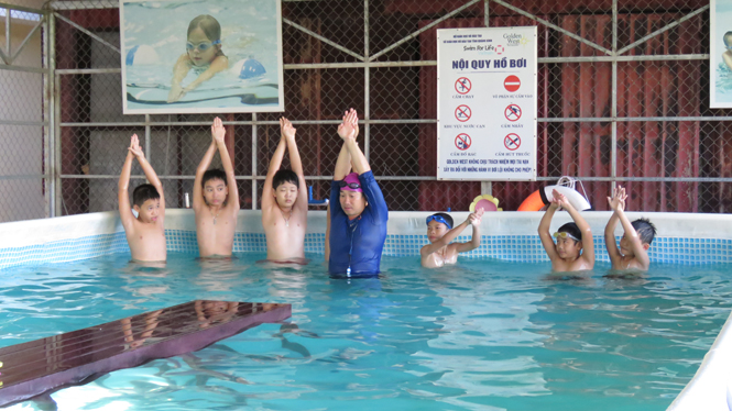 Các giáo viên hướng dẫn từng động tác bơi an toàn cho trẻ em tại bể bơi di động Trường tiểu học Đồng Phú.