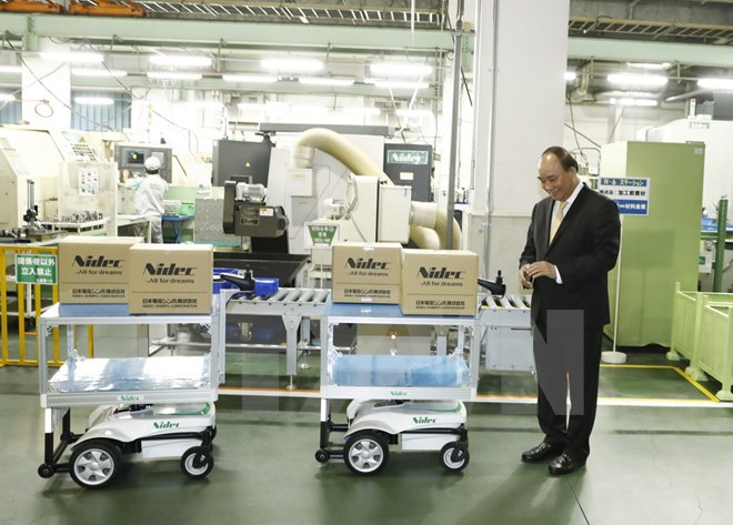 Thủ tướng Nguyễn Xuân Phúc vận hành thử robot i611 tại nhà máy của Tập đoàn Nidec. (Ảnh: Thống Nhất/TTXVN)