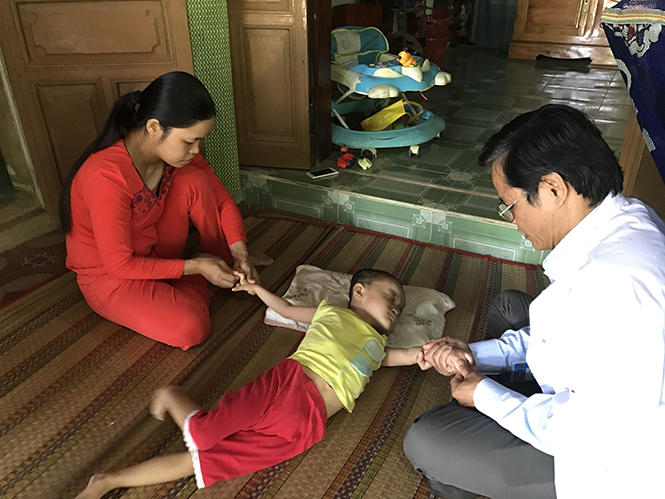 Cán bộ y tế xã Tân Thủy (Lệ Thủy) hướng dẫn cho phụ huynh cách luyện tập, phục hồi chức năng cho trẻ khuyết tật.