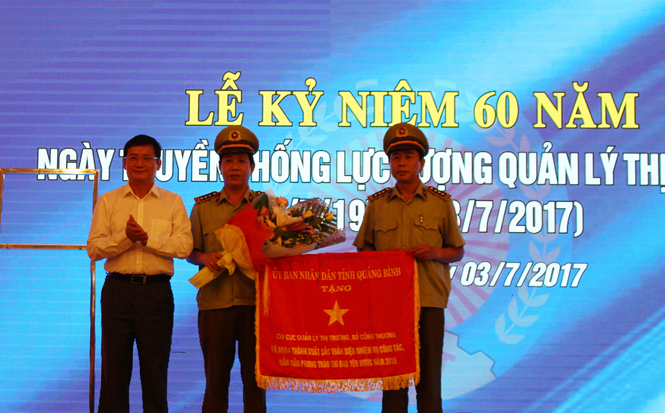 Đồng chí Trần Tiến Dũng, Tỉnh ủy viên, Phó Chủ tịch UBND tỉnh trao cờ thi đua 2016 cho Chi cục QLTT Quảng Bình.