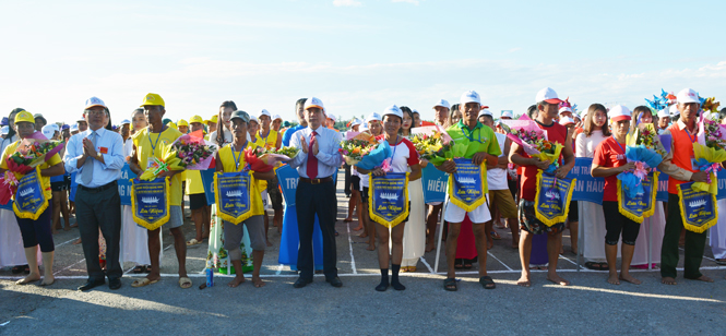 Đại diện lãnh đạo huyện tặng hoa và cờ lưu niệm cho các đội tham gia đua bơi.  