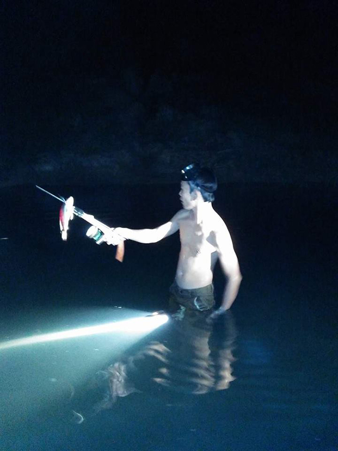  Một thợ lặn vừa bắn được cá trong đêm.