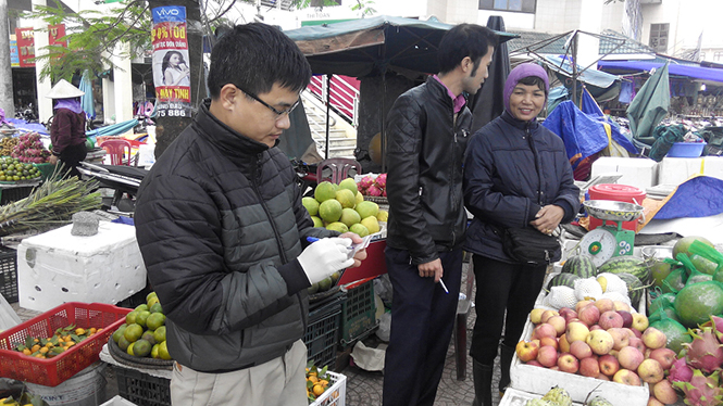 Cán bộ làm công tác bảo đảm ATTP thực hiện lấy mẫu kiểm tra chất lượng thực phẩm ở chợ Đồng Hới.