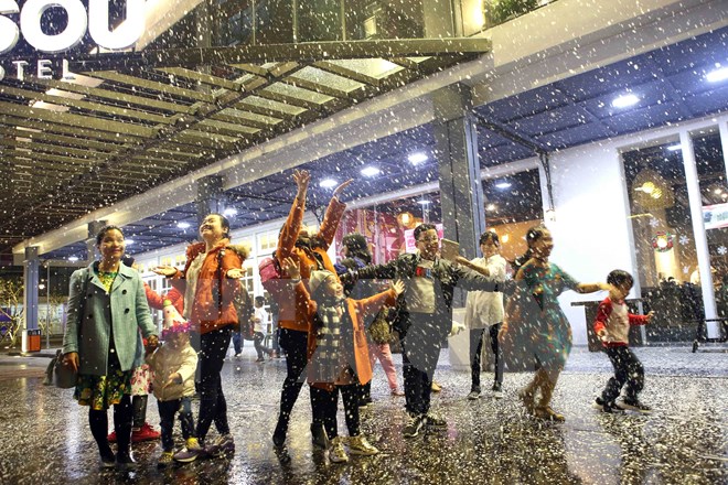 Người lớn và trẻ em hào hứng vui chơi dưới trời mưa tuyết nhân tạo tại Cocobay Đà Nẵng. (Ảnh: Trần Lê Lâm/TTXVN)