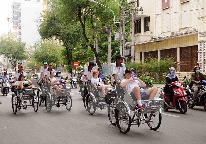 Du khách quốc tế tham quan Thành phố Hồ Chí Minh bằng xích lô. (Ảnh: An Hiếu/TTXVN)