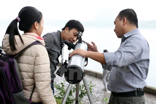  Chuyên gia Đặng Vũ Tuấn Sơn (phải) hướng dẫn các bạn trẻ sử dụng kính thiên văn để quan sát. (Ảnh: Vietnam+)