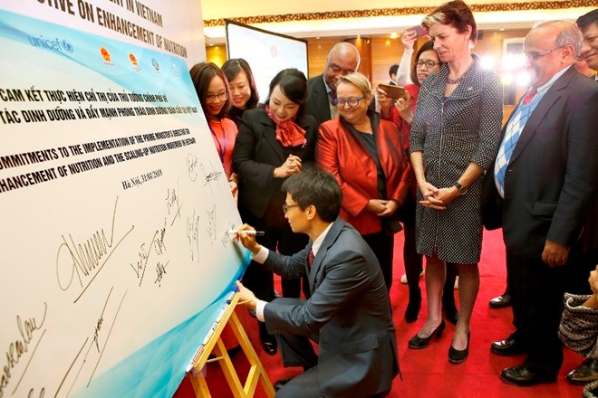  Phó Thủ tướng Vũ Đức Đam ký cam kết hưởng ứng Lễ phát động phong trào đẩy mạnh dinh dưỡng toàn cầu tại Việt Nam. (Ảnh: Dương Ngọc/TTXVN)