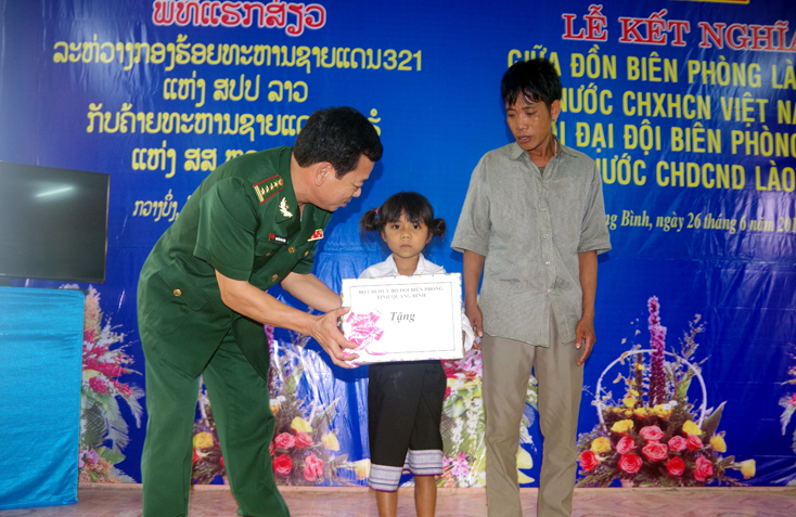 Đại tá Nguyễn Văn Thiện, Chỉ huy trưởng BĐBP Quảng Bình tặng quà cho em Hồ Thị Ngần, học sinh lớp 1, trường Nội trú bản Pha Băng, huyện Sê Pôn, tỉnh Savannakhet (Lào).